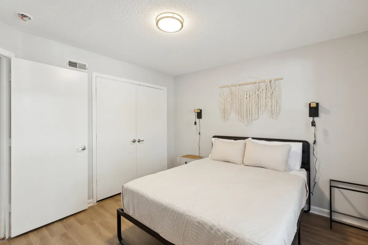 A serene bedroom scene with a plush queen bed, elegant wall art, and soft lighting fixtures that create a cozy, restful ambiance. The inviting bed takes center stage, offering a glimpse of an ideal personal retreat.