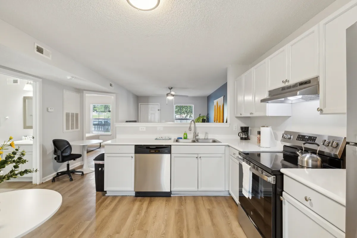 This image features a modern, inviting kitchen with a spacious island, stainless steel appliances, white cabinetry, and an adjoining dining area. The room exudes a welcoming and contemporary atmosphere, ideal for cooking, entertaining, and family gatherings. The open-plan layout highlights the seamless connection between the kitchen and dining space.