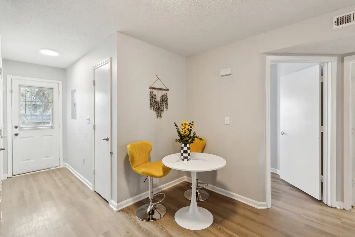 A cheerful interior dining area, featuring vibrant yellow chairs around a round table with a fresh flower arrangement. The room is bathed in natural light, creating a bright and energizing space suitable for morning coffee or casual meetings.