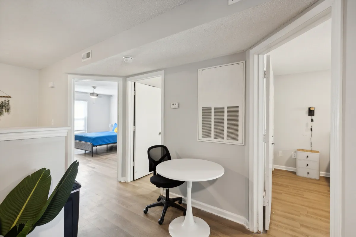 A cozy, sunlit nook with a small round table, sleek black chair, and flourishing green plant. The open doorways and abundant natural light evoke a sense of connection between interior and exterior spaces, encouraging relaxation after a day of adventure.