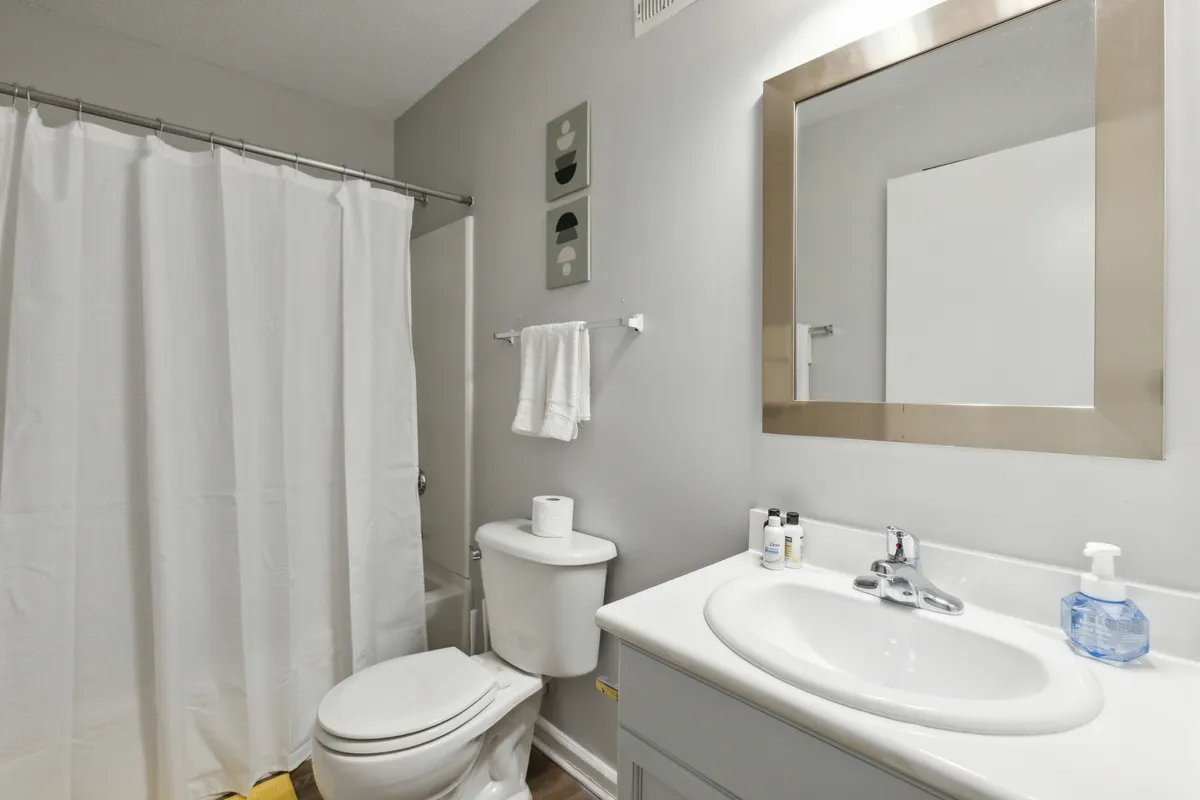 A bright, fresh bathroom with a modern sink and large mirror, a walk-in shower, and a toilet. The clean lines and inviting atmosphere suggest comfort and convenience for guests returning from a day out.