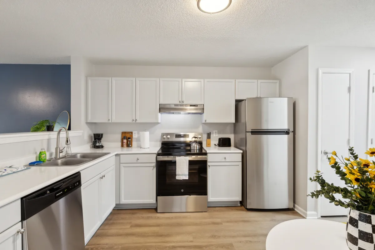 This image spotlights a functional kitchen with sleek stainless steel appliances, crisp white cabinetry, and a modern sink. The setup is practical and stylish, ideal for cooking, entertaining, and preparing family meals.